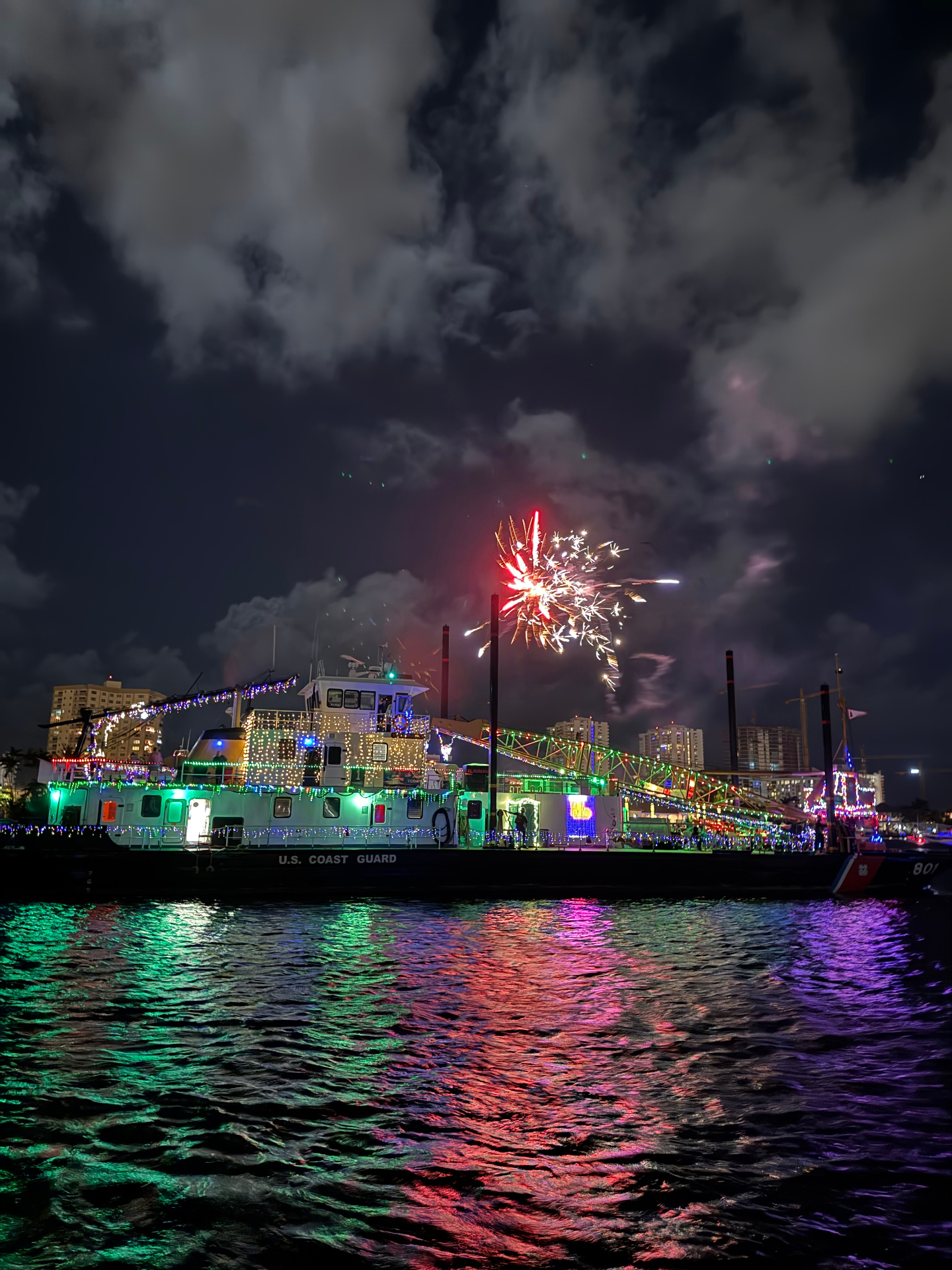 Decorated Coast Guard vessel under fireworks at night