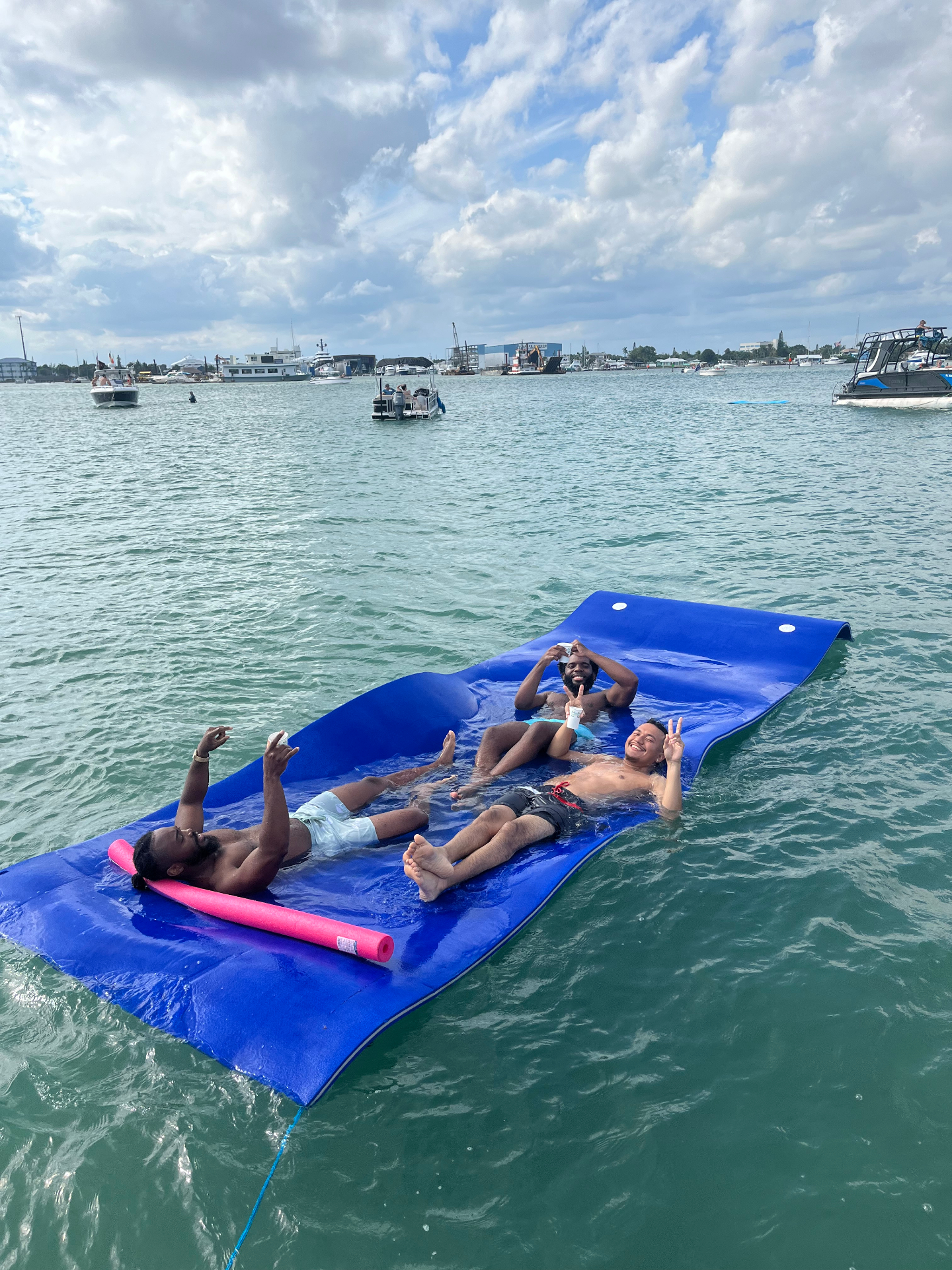 Friends floating on a water mat in the harbor