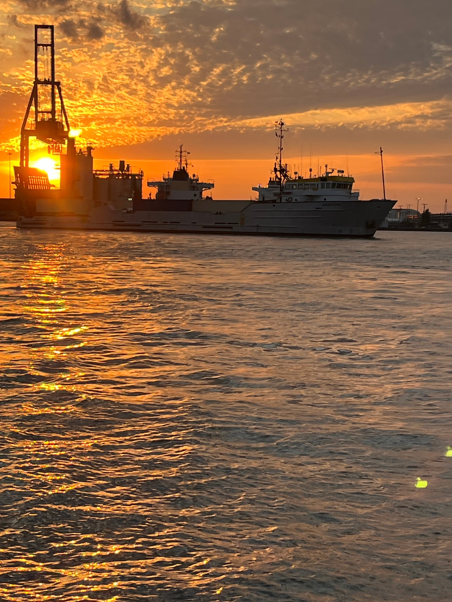 Cargo ship crossing the water at golden sunset