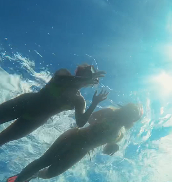 Snorkelers swimming toward the surface in bright sunlight